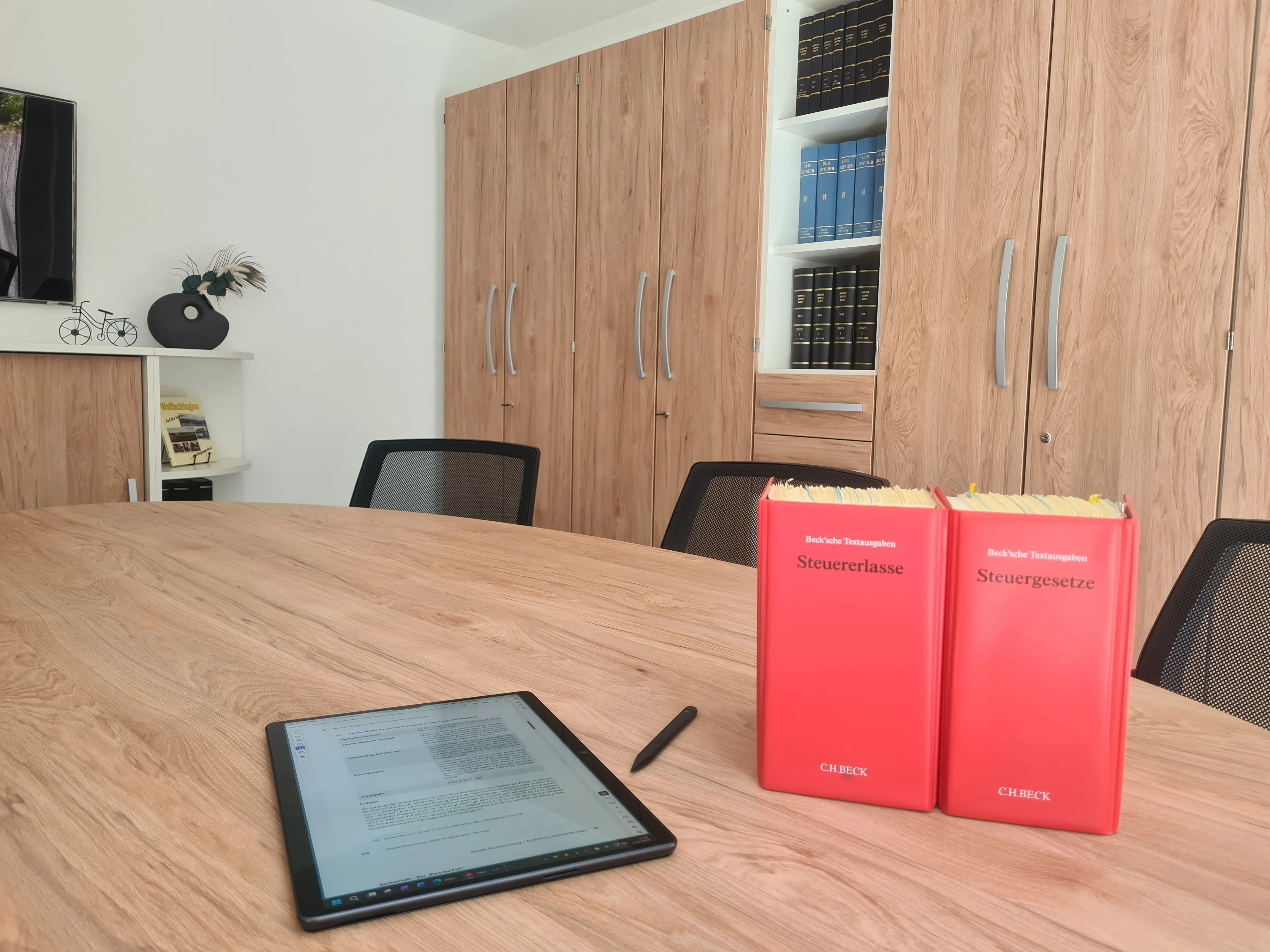 Besprechungsraum der Steuerkanzlei mit Tablet sowie Fachbüchern zu Steuererlassen und Steuergesetzen